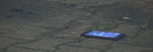 Ein Smartphone liegt auf einem gepflasterten Untergrund.